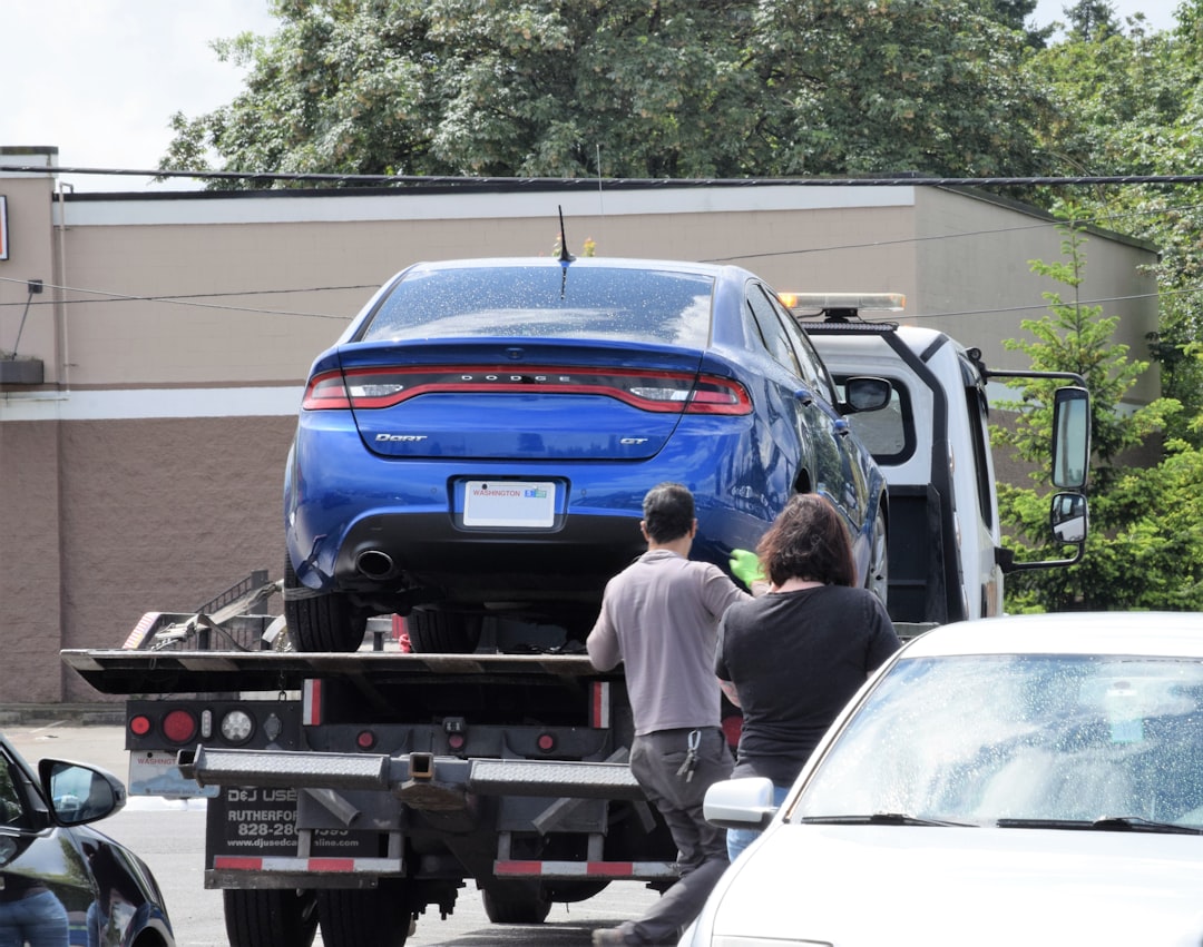 a-blue-car-being-loaded-onto-a-flatbed-truck-uanilb8zkta